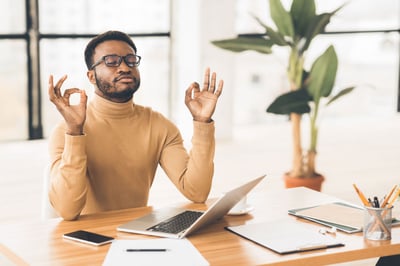 Man meditating at desk in home office