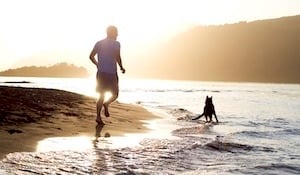 Man running on the beach with a dog