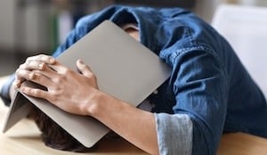 Employee hiding under laptop